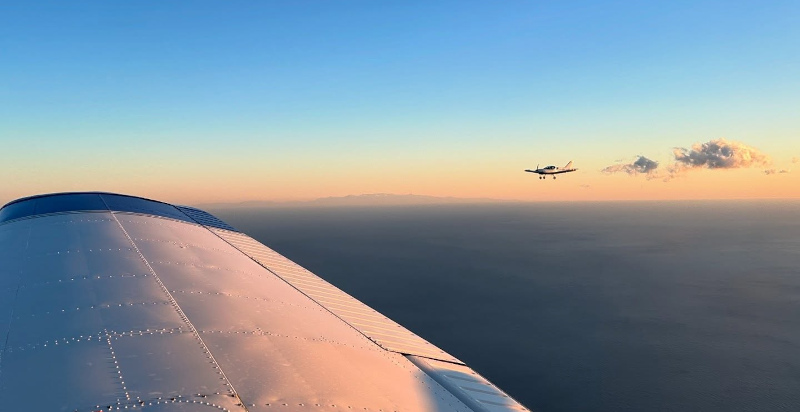 L'aereo in volo al tramonto, con lo sfondo dorato del cielo sopra l'aeroporto di Villanova d'Albenga