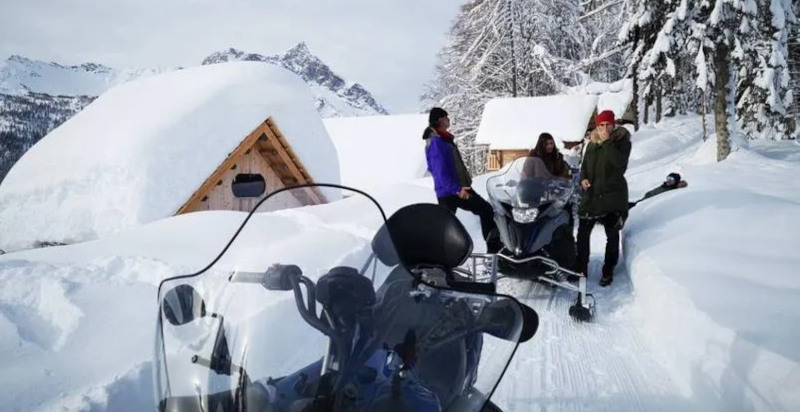 Esperienza di cena in baita con motoslitta tra neve e montagna