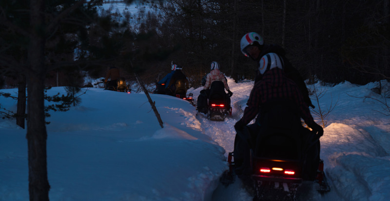 tramonto buio bosco motoslitte guidatori con passegeri a Sauze di Cesana zona Sestriere